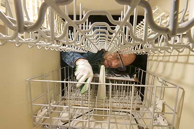 An appliance service technician repairing a dishwasher.